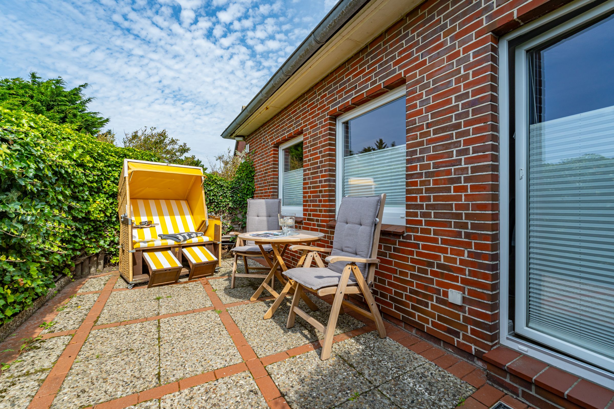 Terrasse, gelber Strandkorb, Tisch und zwei Stühle