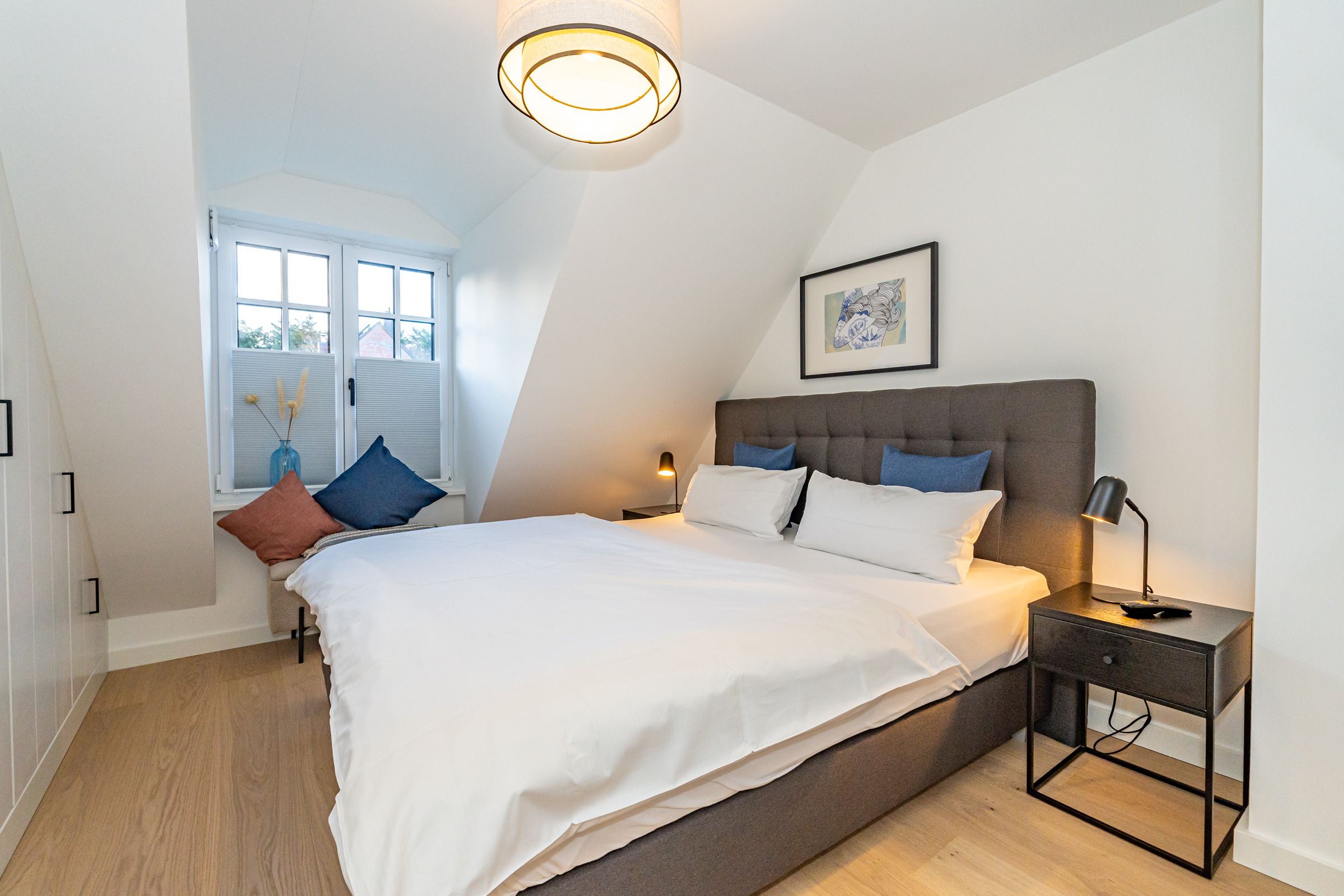 Schlafzimmer mit Doppelbett und Nachttischen. Blick auf den Garten