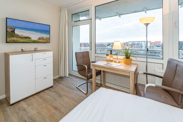 Essbereich mit Tisch und zwei Stühlen. Blick auf TV und Westerland.