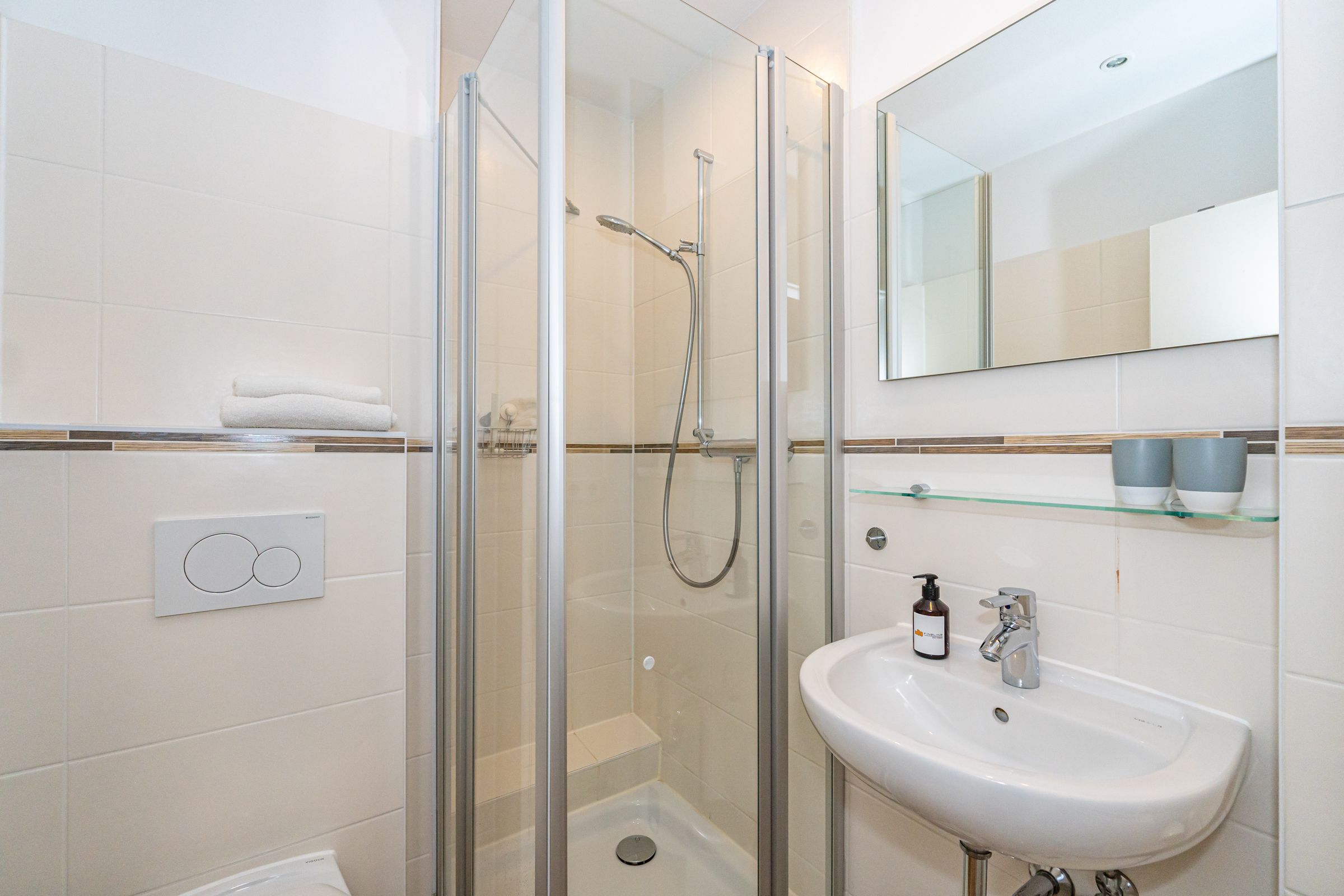 Badezimmer mit kleinem Waschbecken, Spiegel und Dusche