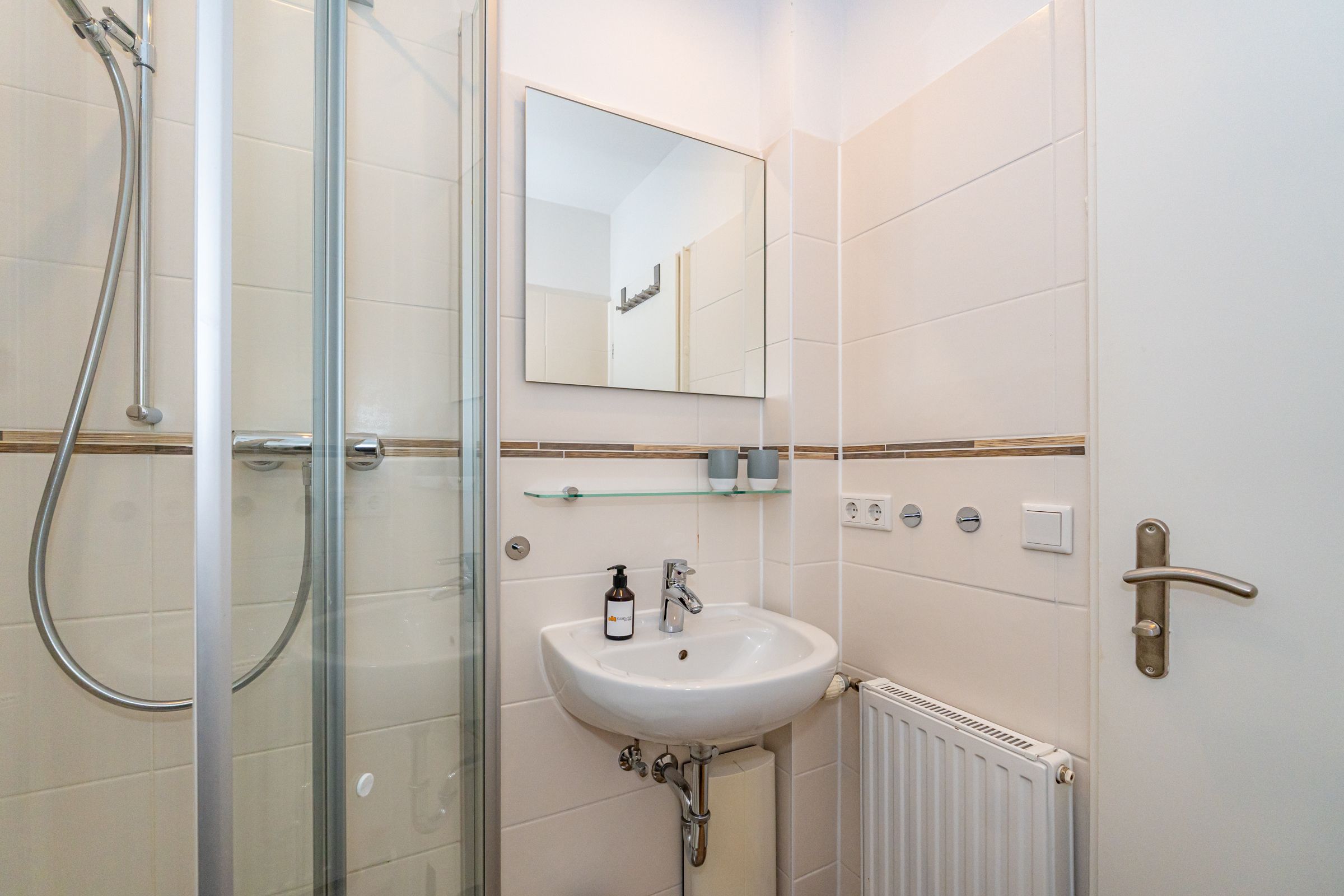 Badezimmer mit kleinem Waschbecken, Spiegel und Dusche.