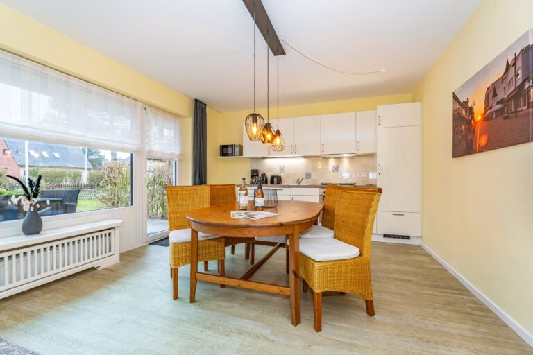 Esstisch mit vier Stühlen. Im Hintergrund die Küchenzeile.