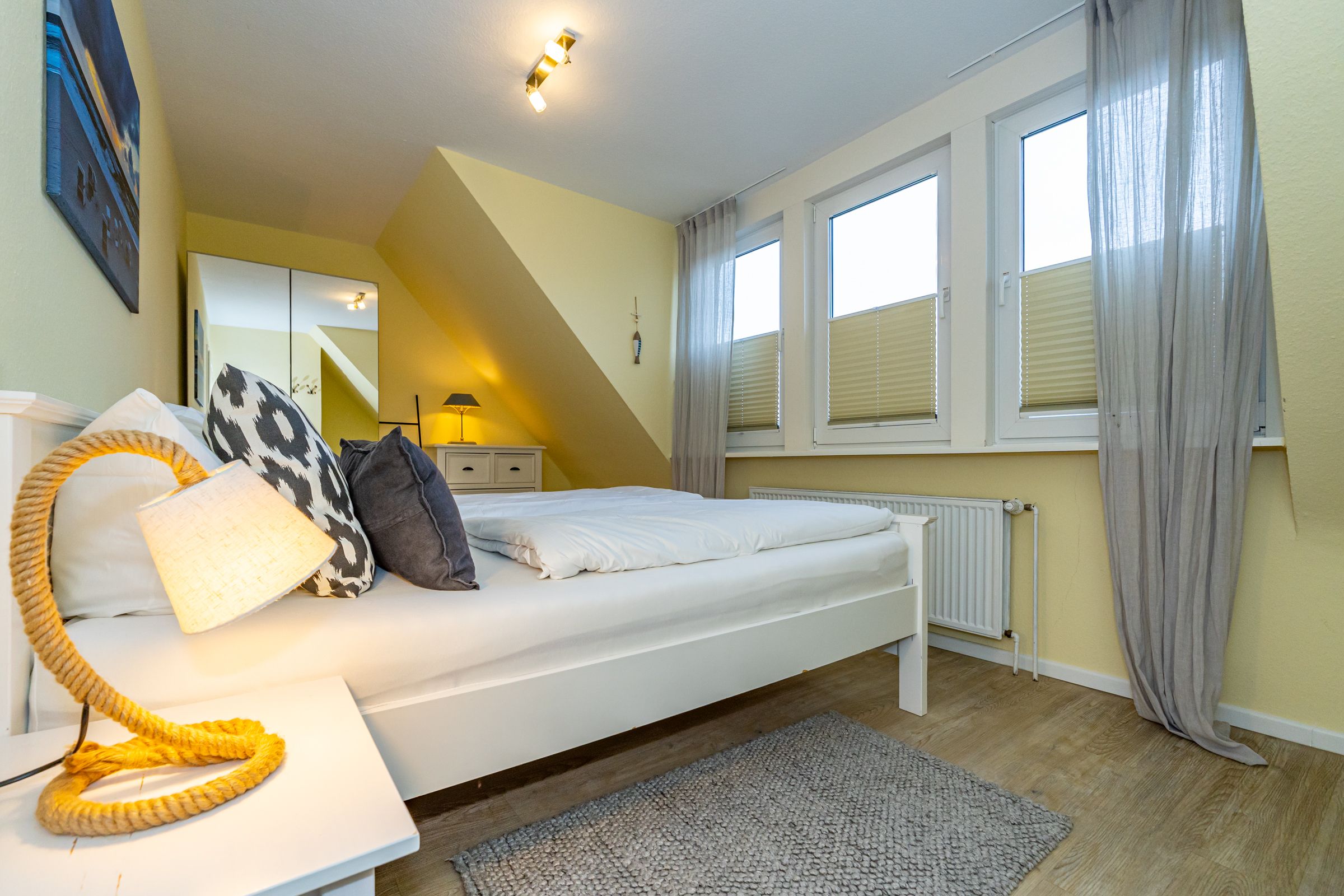 Schlafzimmer mit Doppelbett und kleinem Kleiderschrank und Blick auf den Garten.