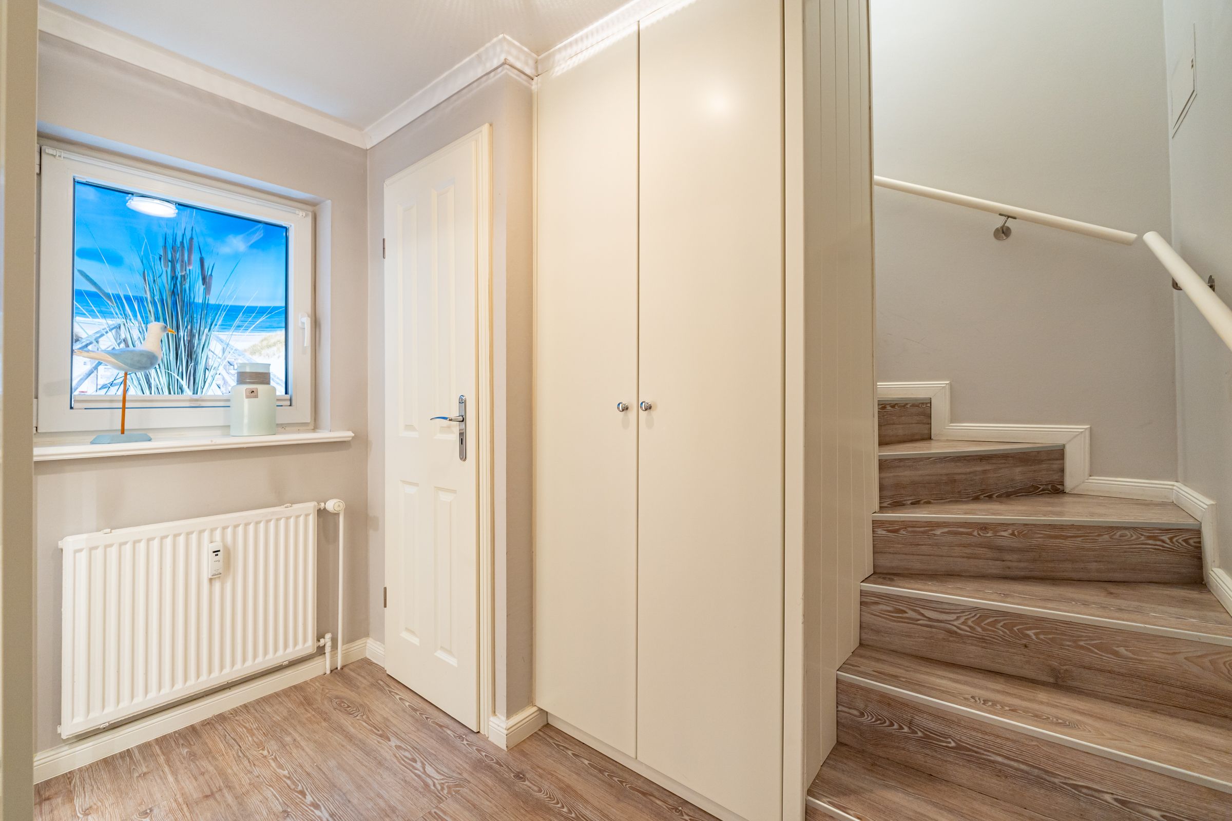 Flur im Untergeschoss mit kleinem Schrank und Treppe ins Erdgeschoss