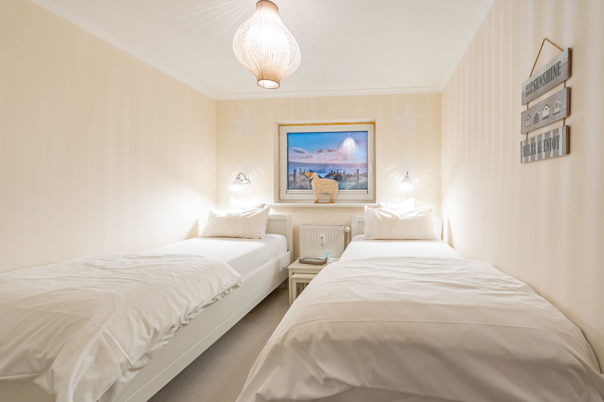 Schlafzimmer mit zwei Einzelbetten und Dekortationsartikeln an der Wand und am Fenster