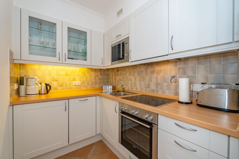 Eckküchenzeile mit flächenbündigen Hängeschränken. Arbeitsbereich mit Herd, Ofen und Waschbecken