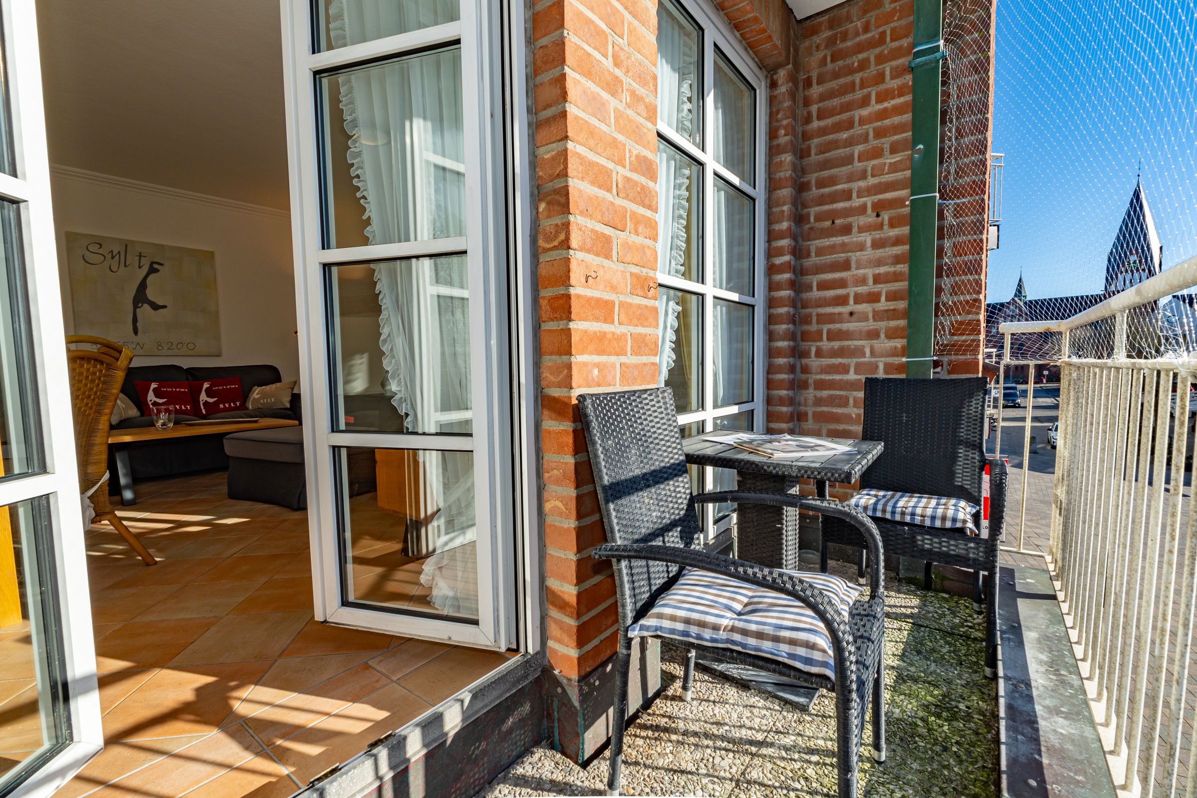 Balkon mit zwei Stühlen und eine Tisch. Im Hintergrund der Eingang zur Wohnung