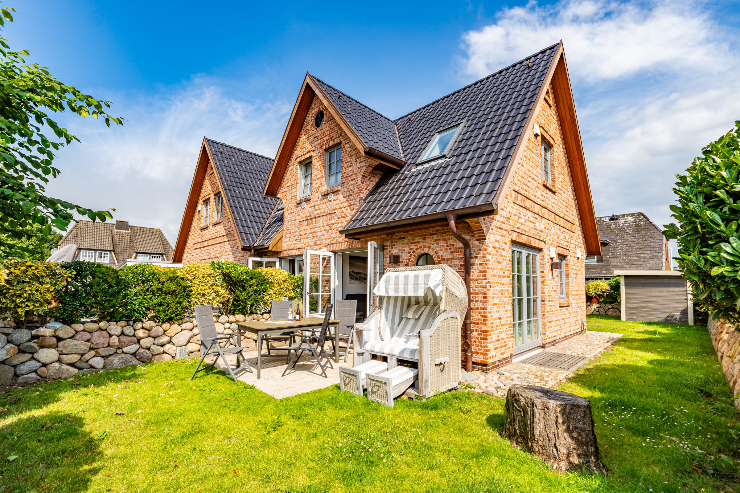 Haus mit Garten. Auf der Terrasse eine Strandkorb und Gartenmöbel